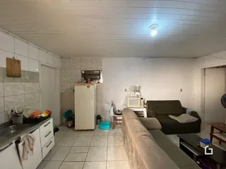 Imagem de uma sala de estar com piso de cerâmica e cozinha integrada.