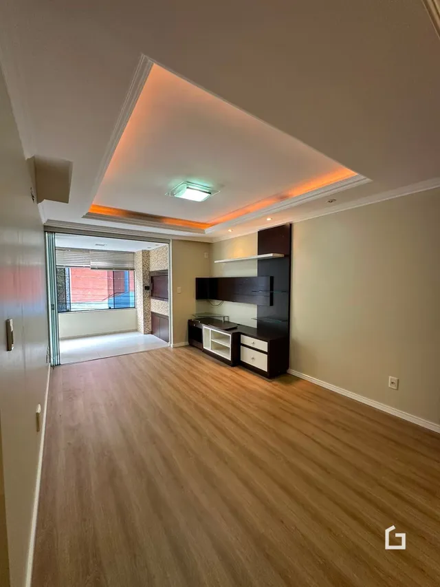 Foto de uma sala com piso de madeira clara e teto em relevo.