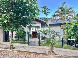 Fachada da residência em Lajeado, Brasil, com cerca e vegetação exuberante.