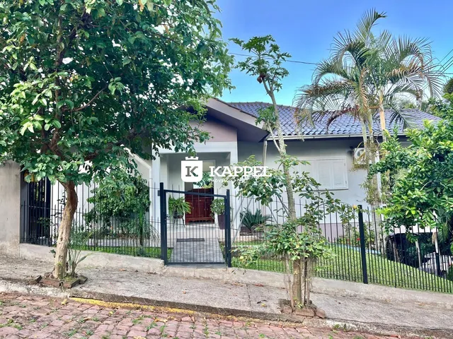 Fachada da residência em Lajeado, Brasil, com cerca e vegetação exuberante.