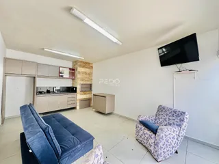 Sala de estar com cozinha integrada e móveis.