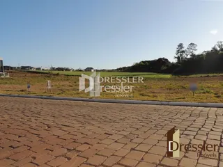 Área externa pavimentada com tijolos na frente da propriedade.