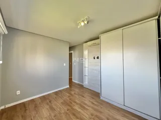 Hall de entrada com piso de madeira e armários embutidos brancos.