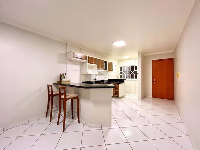Vista interna de uma cozinha com armários brancos e piso de cerâmica clara.