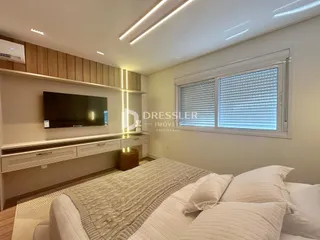 Quarto com cabeceira e televisão montada na parede.