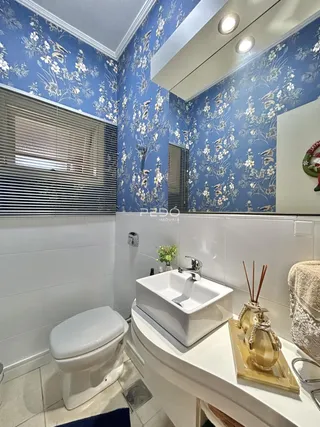 Banheiro com revestimento azul floral e piso cerâmico claro.