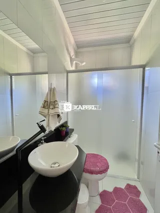 Banheiro moderno com pias brancas e revestimento claro.