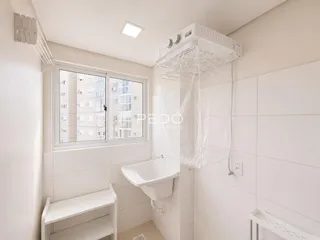 Foto de um banheiro com revestimento cerâmico branco e janela.