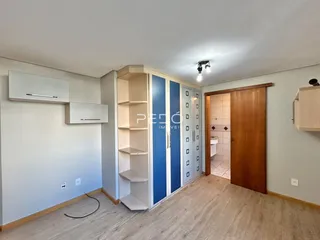 Ambiente interno de uma sala com piso de madeira e armários embutidos.