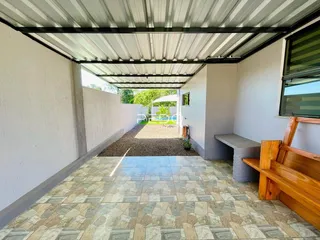 Área externa pavimentada com piso de cerâmica e vista para o jardim e piscina.