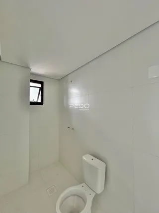 Foto de um banheiro interno com revestimento branco e piso claro.