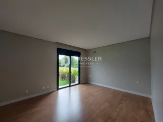 Vista interna de uma sala com piso de madeira e porta de vidro.