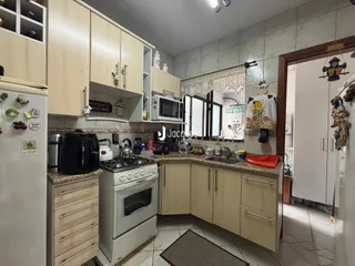 Cozinha com armários de madeira clara e piso de cerâmica.