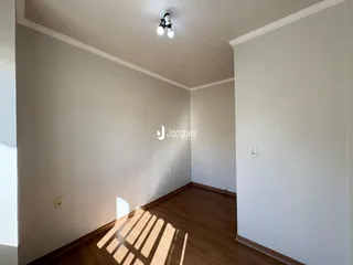 Corredor com piso de madeira e paredes brancas em uma residência.