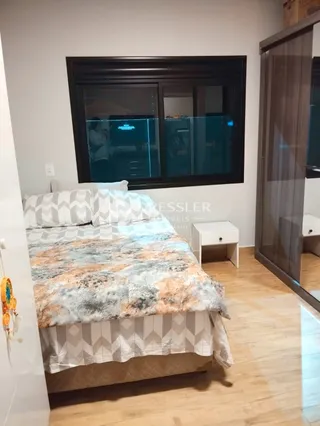 Quarto com cama e piso de madeira clara.