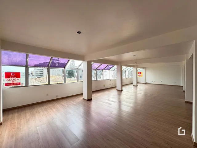 Um espaço amplo com piso de madeira e grandes janelas.