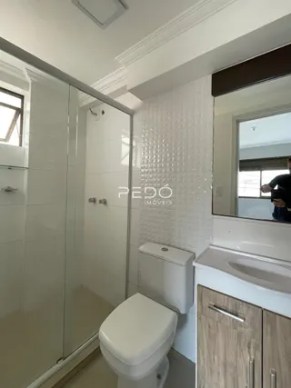 Foto de um banheiro com revestimento branco e box de vidro.