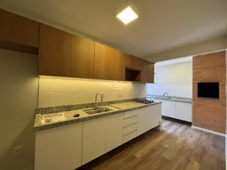 Vista da cozinha com armários de madeira e bancadas claras.