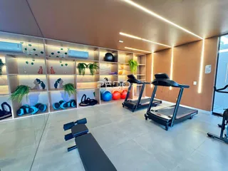 Ambiente interno de uma sala com equipamentos de ginástica e estantes.