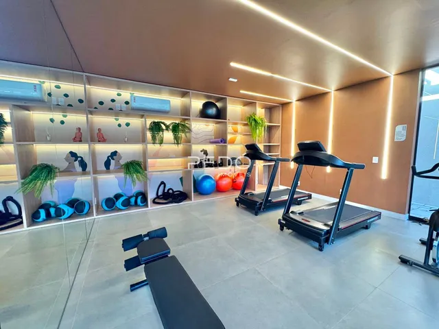 Ambiente interno de uma sala com equipamentos de ginástica e estantes.