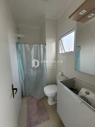 Foto de um banheiro interno com cortina azul e vaso sanitário branco.