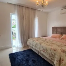 Quarto com cama e cortinas brancas em um imóvel.