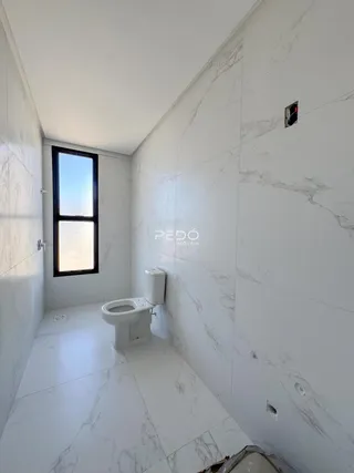 Corredor interno com paredes de mármore branco e piso claro.