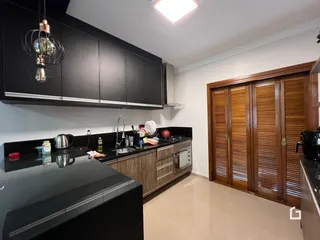 Cozinha moderna com armários escuros e bancadas pretas.