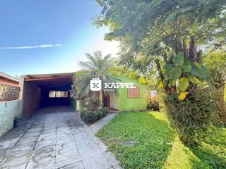 Foto da fachada de uma casa verde com um pátio pavimentado.
