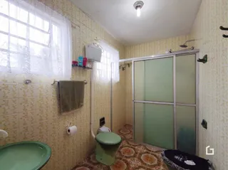 Foto de um banheiro interno com azulejos amarelos e um vaso sanitário verde.