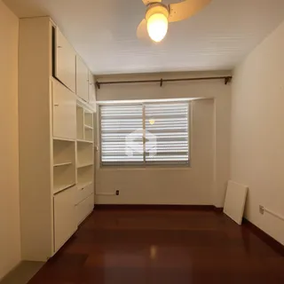 Ambiente interno de uma sala com piso de madeira e armários brancos.