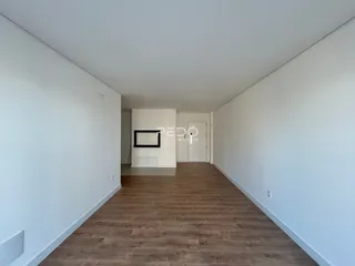 Um corredor interior com piso de madeira e paredes brancas.
