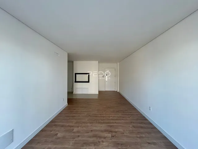 Um corredor interior com piso de madeira e paredes brancas.