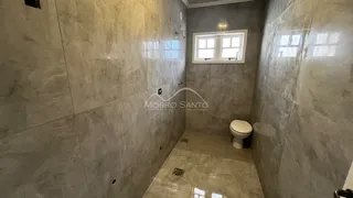 Foto interna de um banheiro com paredes revestidas em azulejos cinzas.