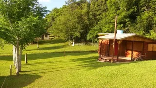 Vista externa de uma propriedade rural com gramado verde e vegetação densa.