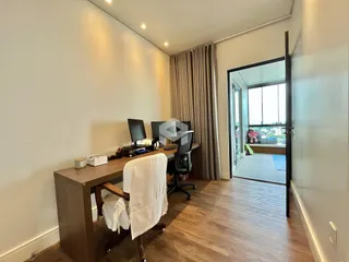 Uma sala de escritório com piso de madeira e porta de vidro que dá acesso a outra área.
