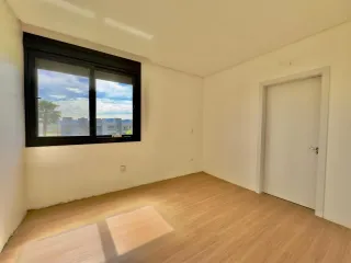 Sala de estar com piso de madeira e grande janela mostrando a vista externa.