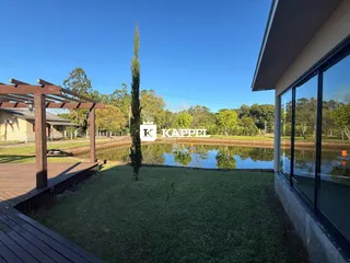 Vista externa mostrando um jardim com um lago e uma área de deck de madeira.