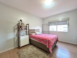 Quarto com cama e estante de madeira em um imóvel no Brasil.