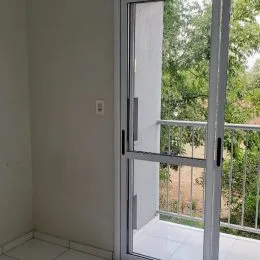 Vista de uma porta de vidro com sacada em um imóvel.
