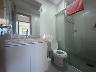 Interior de um banheiro moderno com box de vidro e vaso sanitário branco.