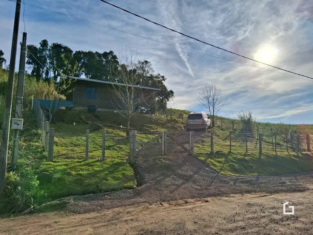 Vista externa de uma propriedade rural com cerca e terreno gramado.