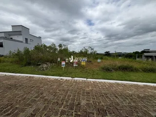 Vista externa de uma propriedade com vegetação densa e sinais no fundo.