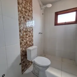 Foto de um banheiro com vaso sanitário branco e revestimento de azulejos.