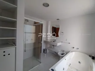 Foto interna de um banheiro com banheira e paredes brancas.
