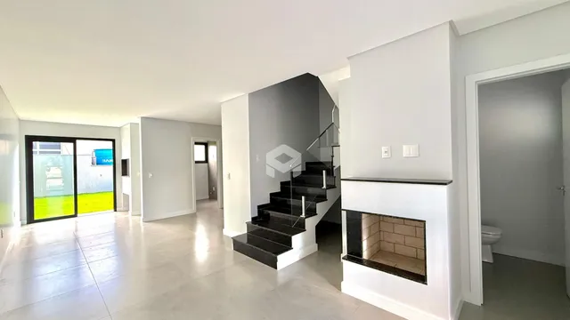 A sala de estar moderna apresenta um piso claro e uma escadaria com guarda-corpo de vidro.