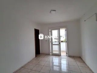 Uma sala de estar clara com piso de cerâmica e porta de vidro que dá acesso a uma área externa.