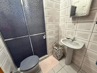 Foto interna de um banheiro com revestimento cerâmico e box de vidro.