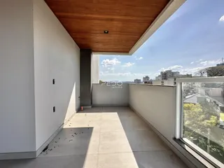 Vista de uma varanda moderna com piso de cerâmica e teto de madeira.