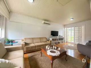 Sala de estar com sofá e piso de madeira clara em um imóvel no Brasil.